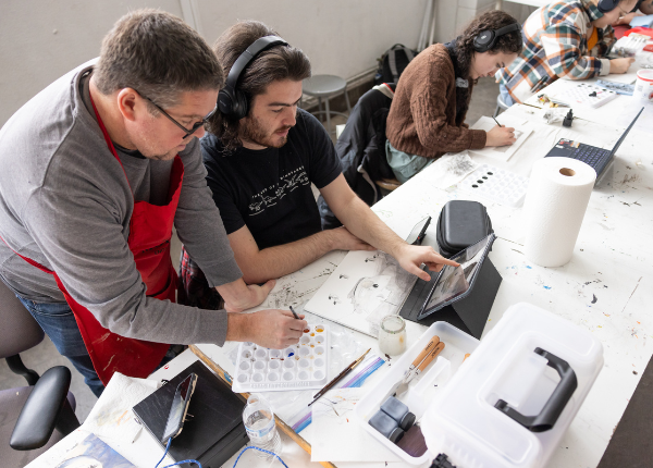 An art student is assisted by a faculty member to assess a project..