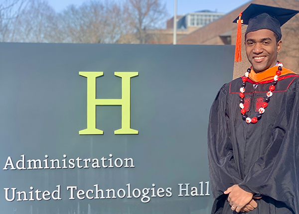 young man at graduation in front of building sign