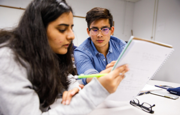 Two UHart students reviewing homework on a notebook.